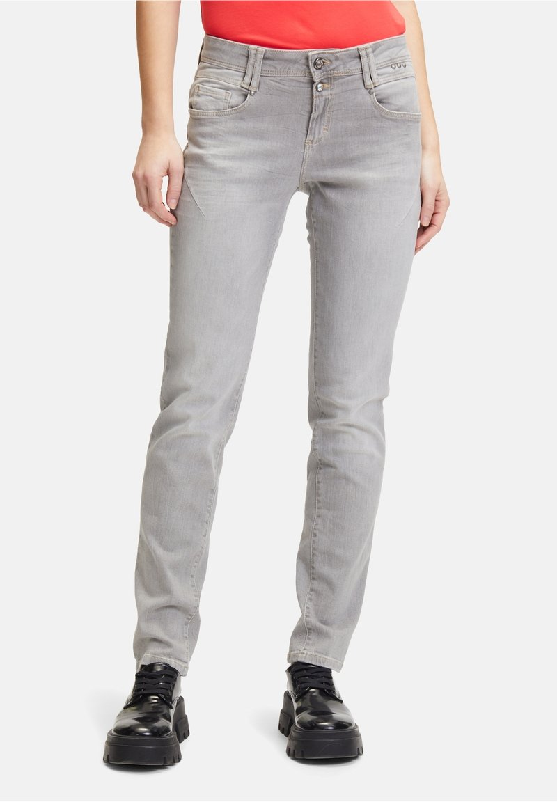 Grå tajta jeans med fem fickor, i en något blekt tvätt, med knäppning framtill och kontrasterande sömmar. Kombineras med svarta kraftiga skor.