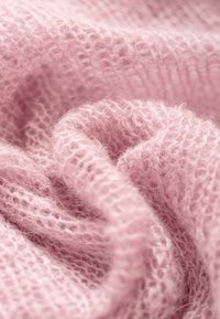 Różowa dzianina jest zaprezentowana w miękkim, teksturowanym wzorze. Materiał wydaje się puszysty i lekki, z widocznymi drobnymi szwami w całej powierzchni.