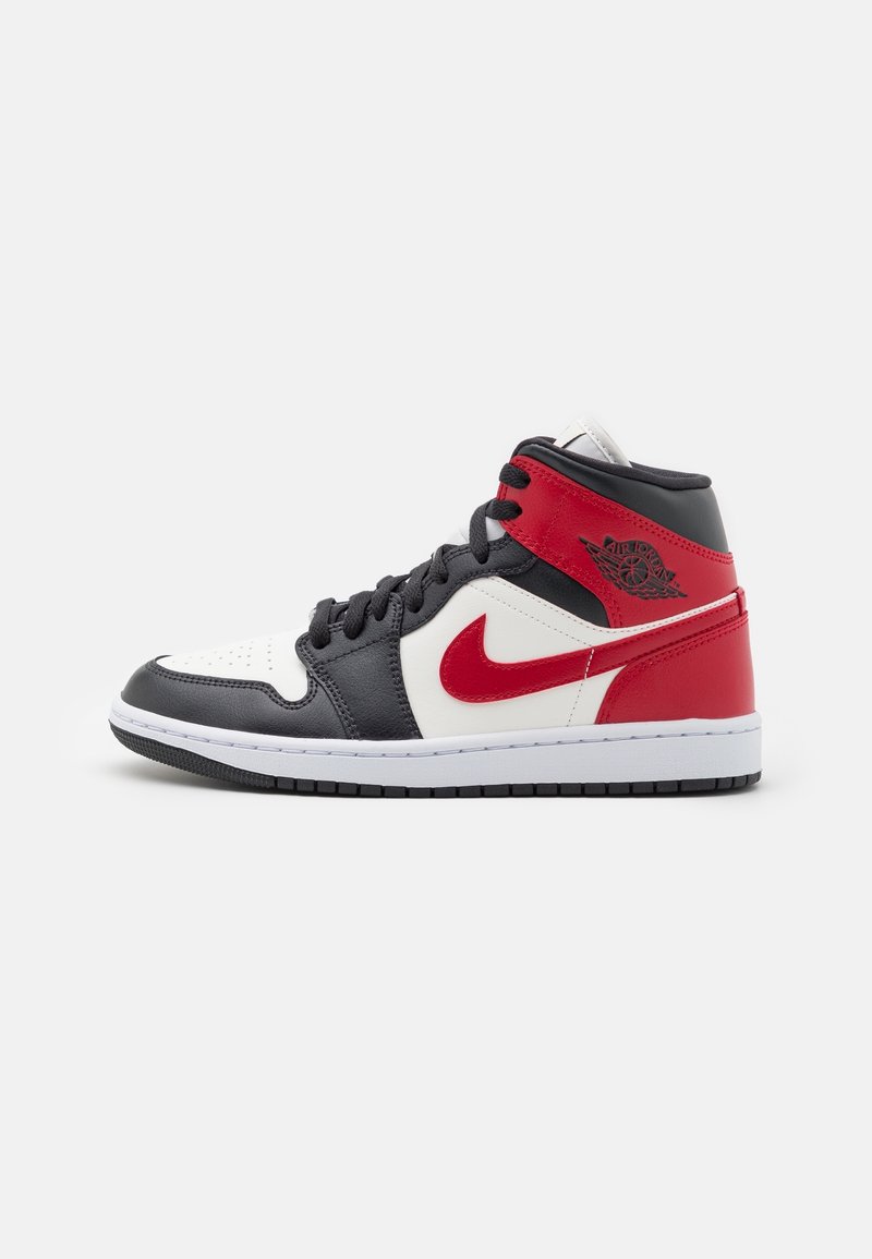 Baskets montantes avec des panneaux en cuir noir, blanc et rouge, le logo rouge Nike Swoosh, des lacets noirs et le logo Air Jordan près de la cheville.