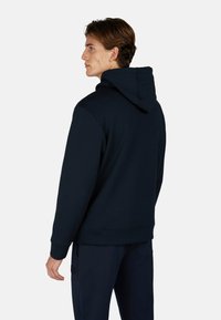 Felpa blu navy con cappuccio regolabile, maniche raglan e polsini a costine. Il tessuto sembra morbido con una texture liscia e un design classico.