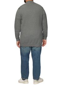 Pull gris à manches longues, col rond et poignets côtelés. Associé à un jean bleu et des baskets blanches, vu de dos.