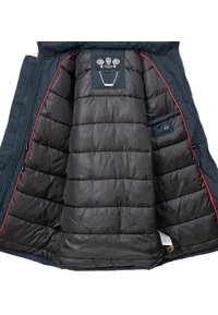 Interiorul unei jachete puffer de culoare albastră închisă, cu căptușeală neagră matlasată, detalii roșii și un buzunar mic. Prezintă o etichetă cu un design decorativ la gât.