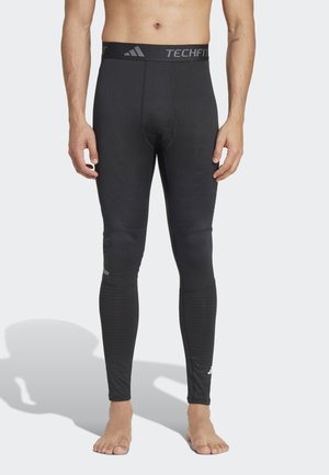 Leggings de compressão pretos com uma ampla cintura elástica rotulada "TECHFIT." Apresentam painéis texturizados nas pernas inferiores. Acabamento suave em geral.