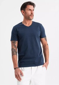T-shirt a V in blu navy realizzato in cotone solido con maniche corte, caratterizzato da un design aderente e una texture liscia.