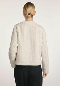 Biały, teksturowany sweter z wzorem w warkocze, okrągłym dekoltem i długimi rękawami. Miękka, puszysta tkanina z odkrytymi plecami.