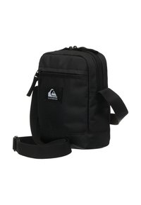 Borsa a spalla nera realizzata in tessuto resistente, dotata di chiusura con zip, cinturino regolabile e una patch con il logo sul davanti. Design compatto.