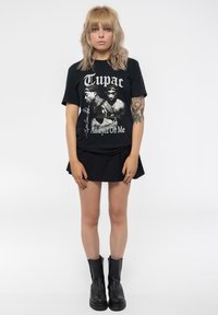Black T-shirt with a graphic print of two figures, text "Tupac" and "All Eyez On Me," worn with a black skirt and black ankle boots.