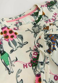 Datasæt T-shirt i 100% bomuld med et sjovt design med stiliserede hunde iført forskellige trøjer, hovedsageligt i kremfarve med multikolorede accenter og mønstre.