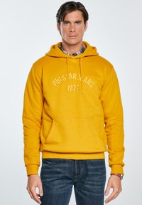Żółta bluza z kapturem z przednią kieszenią, z nadrukowanym na białym tle "BIG STAR JEANS" i "1979". Żebrowane mankiety i pas, miękka faktura.