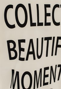 Tessuto bianco con grande testo nero che recita "COLLEZIONA MOMENTI BEAUTIFICA." Tipografia semplice e audace senza ulteriori accenti.