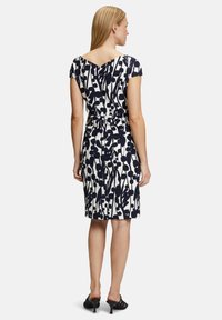 Robe à imprimé floral présentant des couleurs marine et crème, des manches courtes, un dos en V et une taille cintrée avec un détail de lien.