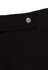 Czarna tkanina z zbliżeniem na srebrny okrągły guzik na złożonym klapie, podkreślająca detale i teksturę materiału odzieżowego.