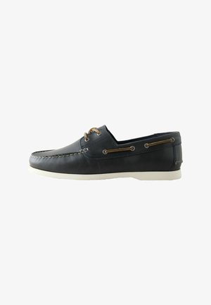 Czarny skórzany but typu boat shoe z białą podeszwą, brązowym detaltem sznurowadeł wokół boków oraz dwoma oczkami z brązowymi sznurówkami na górze, widok z boku.
