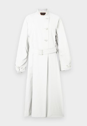 Baltas tranšėjos paltas su aukštu apykakliu, ilgomis rankovėmis ir diržu juosmenyje. Yra trys iškilūs mygtukai ir lygus, matinio paviršiaus apdaila.