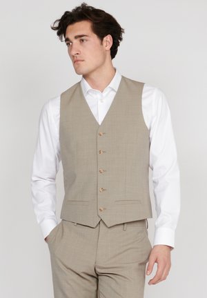 Chaleco beige ajustado con cuello en V, cinco botones de madera y bolsillos laterales, llevado sobre una camisa blanca. Textura suave y diseño entallado.