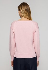 Light pink sweater with long sleeves, ribbed cuffs, and hem. Soft texture, rounded neckline, and raglan sleeve design.