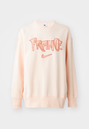 Light peach sweatshirt made of soft fabric featuring bold orange embroidery reading "FRANCE" and a small Nike logo at the bottom.