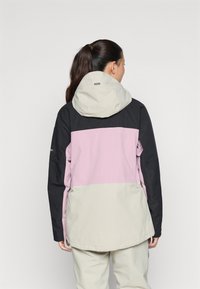 Farbblockierte Jacke mit schwarzen, pinken und beigen Einsätzen, einer Kapuze und einem leicht abgerundeten Saum. Hergestellt aus einem strukturierten, strapazierfähigen Material.