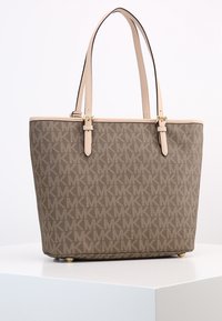 Sac fourre-tout marron avec des poignées en cuir beige, de forme rectangulaire, accents en matériel doré et quatre pieds arrondis en bas.