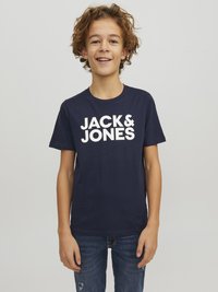 Camiseta de algodón azul marino con una gran impresión blanca de "JACK & JONES" en el pecho. Textura suave y corte estándar. Combinada con jeans azules.