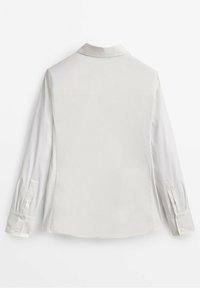 Chemise à manches longues avec un corps gris clair et des manches blanches contrastantes, dotée d'un col et de poignets à boutons. Texture lisse, design minimal.