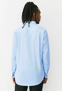 Svetlomodrá košeľa s dlhým rukávom s kockovaným vzorom, zapínanými manžetami a zaobleným lemom. Tkanina pôsobí štruktúrovane a ľahko.