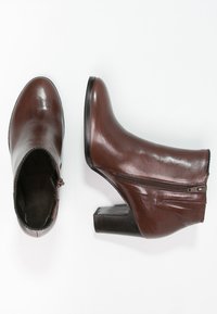 Ruske nahke čevlje do gležnjev z lesketaškim finishem, zadrgo na strani, angularno peto in teksturirane akcenti na zgornjem delu.