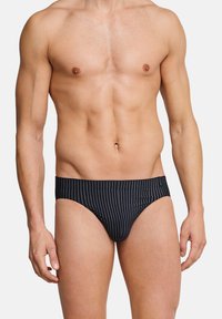 Slip da bagno a righe nere con design a vita bassa, caratterizzati da una texture liscia e un elastico in vita. Nessun marchio o motivo visibile.