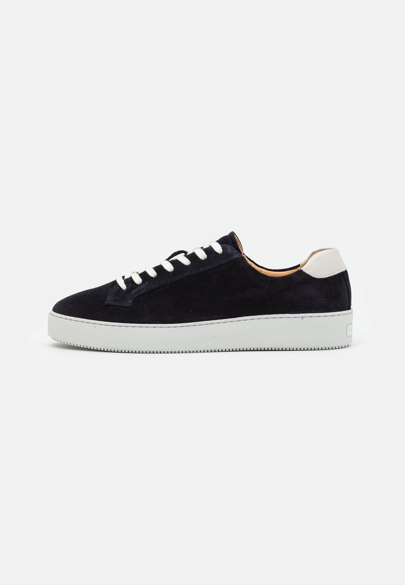 Navy suede sneaker with white laces and heel accent; features a textured rubber sole and rounded toe design.