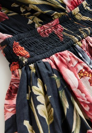 Vestido floral con tejido negro adornado con estampados botánicos en rosa, rojo y verde. Detalles fruncidos elásticos en la cintura. Textura suave.