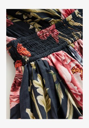 Kukkamekko, jonka mustaa kangasta koristavat vaaleanpunaiset, punaiset ja vihreät kasviaiheet. Elastinen smokkivuoraus vyötäröllä. Pehmeä pinta.