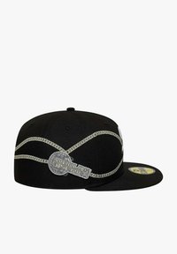 Gorra negra con un diseño estructurado, detalles bordados en plata y un parche circular que dice "WORLD SERIES". Visera plana y estilo ajustado.