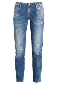 Vaqueros de mezclilla azul con corte ajustado, que presentan un lavado desgastado, detalles desgastados en las rodillas y un diseño de cinco bolsillos estándar con herrajes de metal.