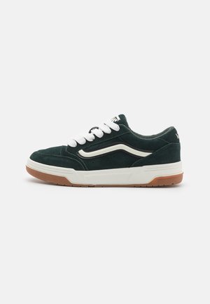 Zapatillas de ante verde con cordones blancos y una suela media color crema. Presenta una suela de goma marrón y un diseño de franja lateral en contraste.