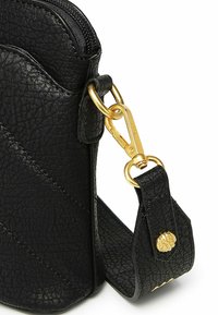 Černá kožená taška s texturou a zlatým kováním, která nabízí zipové uzávěr, odnímatelný popruh a podrobný vzor na připojení popruhu.
