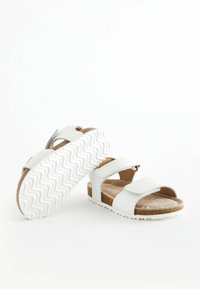 Sandali bianchi con due cinturini regolabili, soletta in sughero e suola in gomma bianca con un motivo a zigzag. Design minimalista.