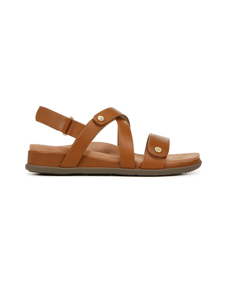 Brown leather sandal featuring cross straps, an adjustable ankle strap, a cushioned footbed, and a flat rubber sole with a small gold accent.