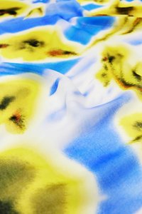 Tessuto multicolore con una texture liscia e setosa. Presenta una miscela di blu, giallo e sottili accenti scuri in un motivo astratto.