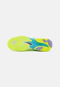 Suela de zapato en amarillo brillante y azul, con goma texturizada que presenta un patrón ondulado y acentos en negro, diseñado para tracción y durabilidad.