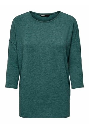 Teal oversized T-shirt made of soft, textured fabric. Features a round neckline and three-quarter sleeves, with a relaxed fit. No patterns or accents.