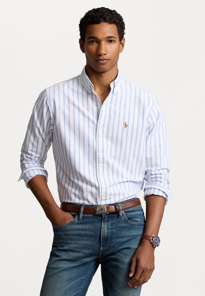 Light blue and white striped button-down shirt made of cotton, featuring long sleeves, a collar, and a small embroidered logo on the chest.