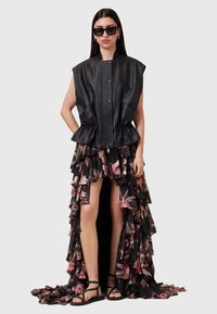 Sort læder uden ærmer top med peplum kant, parret med en voluminøs blomsterprint nederdel, der afslører benet. Stribede sorte sandaler fuldender looket.