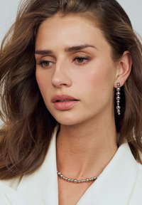 Silverpärlor halsband och matchande hängörhängen; slät ytstruktur, reflekterande yta, olika storlekar på pärlor, bärs med en ljusfärgad topp.