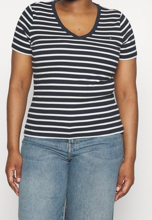 Marineblau-weiß gestreites T-Shirt mit V-Ausschnitt und kurzen Ärmeln, aus weichem Stoff, kombiniert mit hellblauen Jeans.