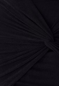 Top nero con tessuto arricciato, creando un effetto torcigliato al centro. Realizzato in un materiale testurizzato e elasticizzato.