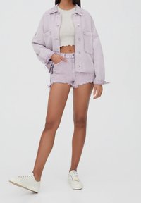 Jasnofioletowa kurtka dżinsowa zestawiona z dopasowanym krótkim topem i postrzępionymi szortami. Dopełnieniem stroju są białe trampki.