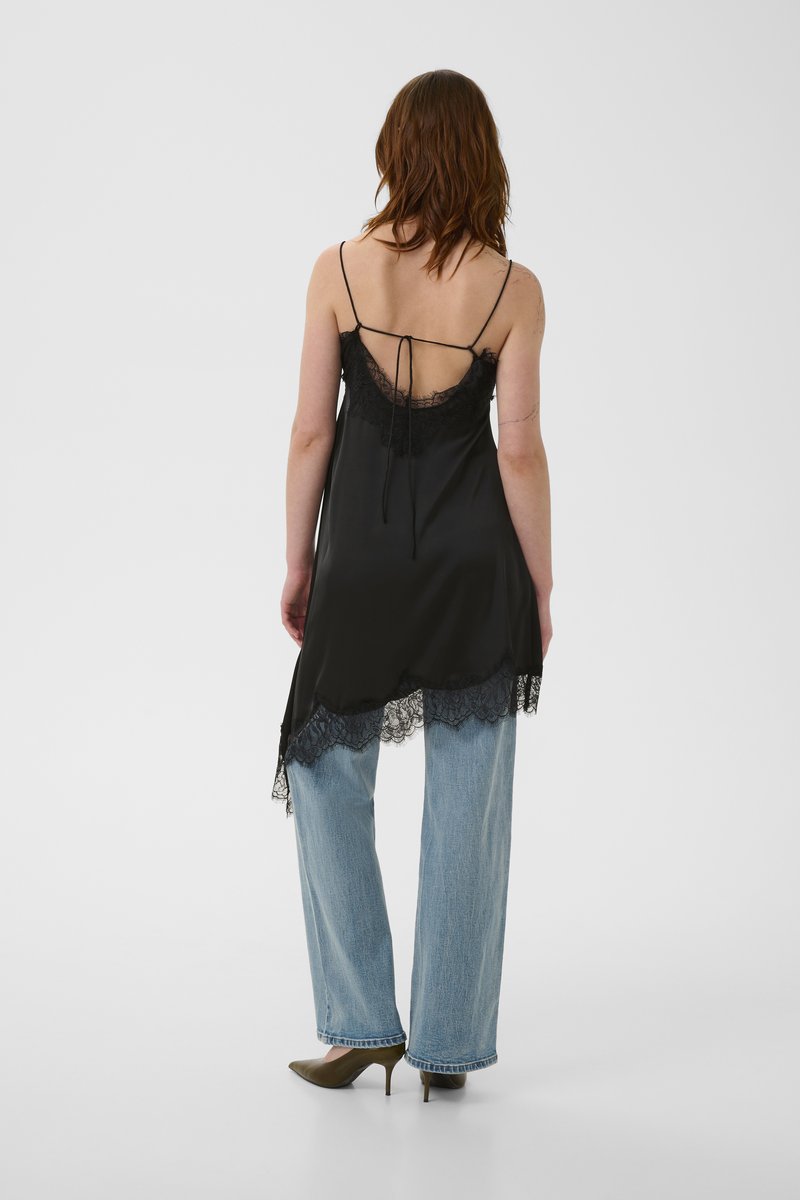 Nuisette en satin noir avec bordure en dentelle, dotée de bretelles spaghetti réglables, d'un dos décolleté et d'une silhouette fluide, associée à un jean bleu clair.