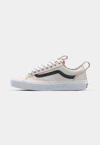 Beige lerret-sneakers med svart sidestripe, hvit gummisåle og grå snører. Har rød fargeklatt bak.