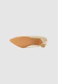 Pompa dorata lucida con punta affusolata e tacco a blocco. La suola esterna è color marrone chiaro con un motivo testurizzato per aderenza. Design minimalista.