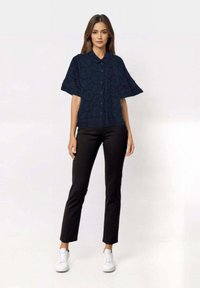 Navy blue short-sleeve button-up shirt with embroidered pattern, paired with fitted black pants and white sneakers.